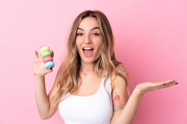 Jovem mulher segurando macarons sobre parede isolada