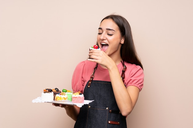 Jovem mulher segurando mini bolos e comê-lo