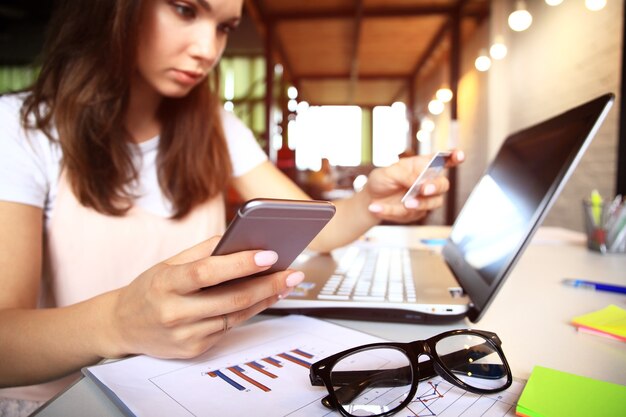 Jovem mulher segurando o cartão de crédito e usando o computador portátil. conceito de compras online.