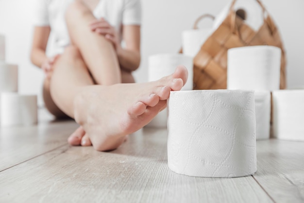 Jovem mulher segurando o rolo de papel higiênico a pé