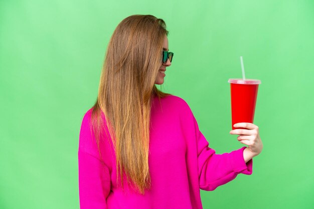 Jovem mulher segurando refrigerante enquanto assiste a um filme 3D com expressão feliz