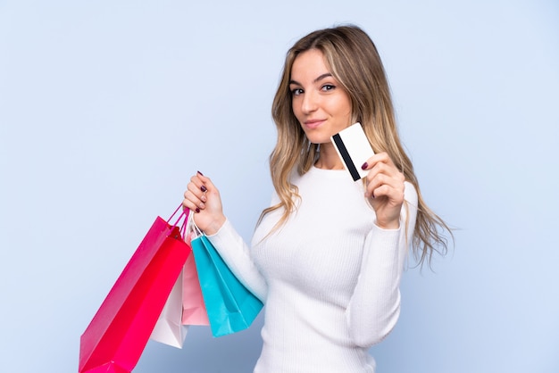 Jovem mulher segurando sacolas de compras e cartão de crédito