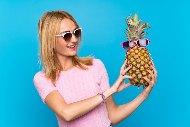 Jovem mulher segurando um abacaxi com óculos de sol