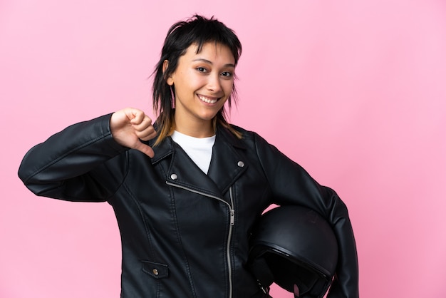 Jovem mulher segurando um capacete de moto isolado rosa orgulhoso e satisfeito