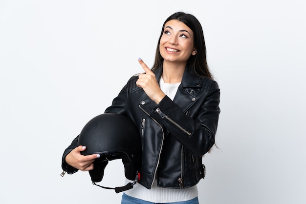 Foto jovem mulher segurando um capacete de moto sobre branco isolado apontando com o dedo indicador uma ótima idéia