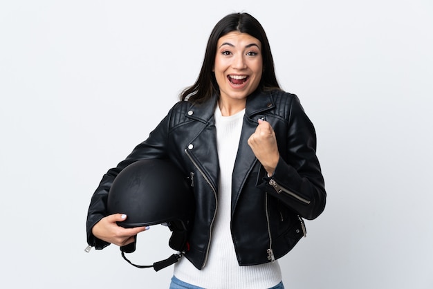 Jovem mulher segurando um capacete de moto sobre branco isolado comemorando uma vitória