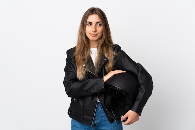 Jovem mulher segurando um capacete de moto sobre branco isolado, pensando uma idéia