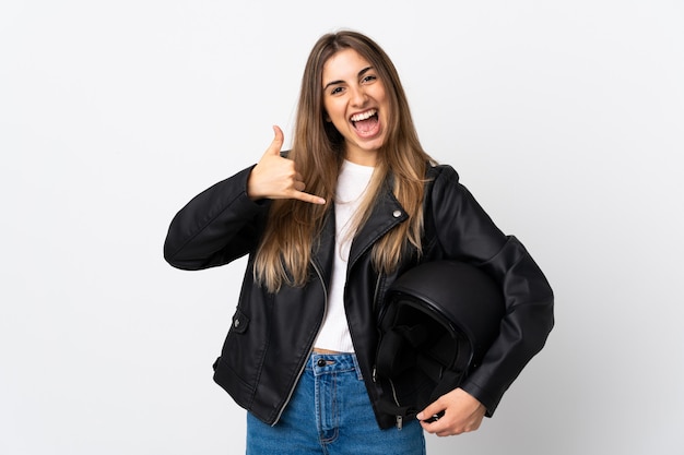 Jovem mulher segurando um capacete de moto sobre parede branca isolada, fazendo gesto de telefone