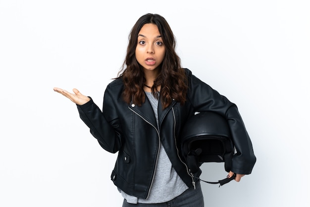 Jovem mulher segurando um capacete de motociclista isolado fazendo um gesto de dúvida