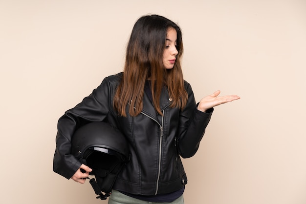 Jovem mulher segurando um capacete sobre parede isolada