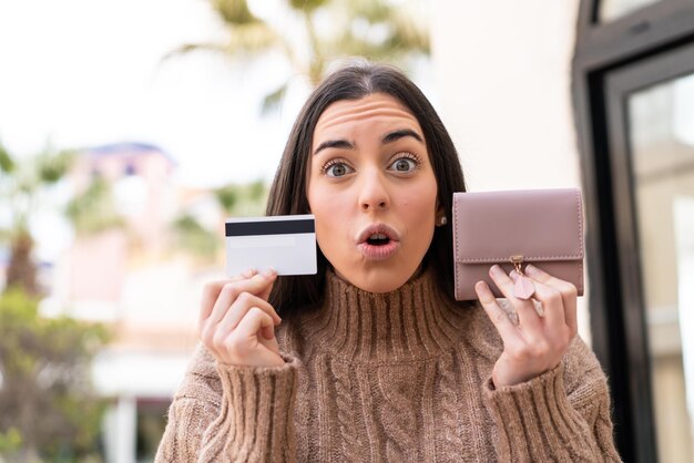 Jovem mulher segurando um cartão de crédito ao ar livre