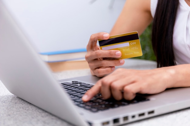 Jovem mulher segurando um cartão de crédito e usando um laptop