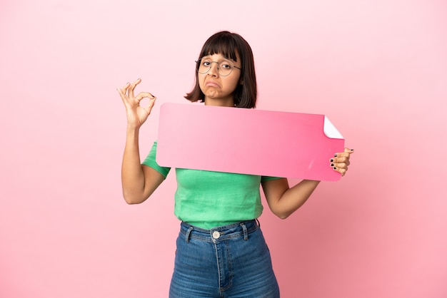 Jovem mulher segurando um cartaz vazio e fazendo sinal de OK