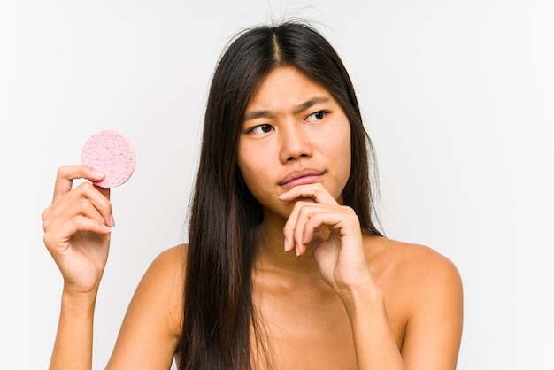 Jovem mulher segurando um disco facial, olhando de soslaio com expressão duvidosa e cética.