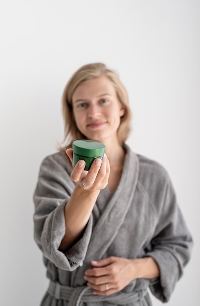 Jovem mulher segurando um frasco com um produto de beleza