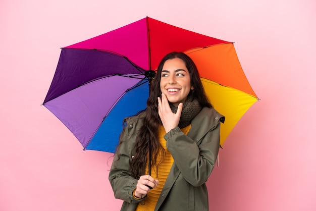 Jovem mulher segurando um guarda-chuva isolada, olhando para cima enquanto sorri