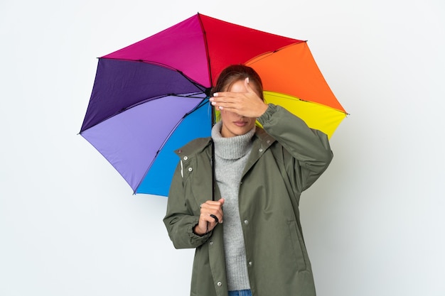 Jovem mulher segurando um guarda-chuva no fundo branco, cobrindo os olhos com as mãos. não quero ver nada