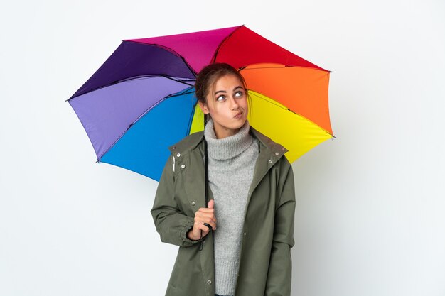 Jovem mulher segurando um guarda-chuva posando isolada contra a parede em branco