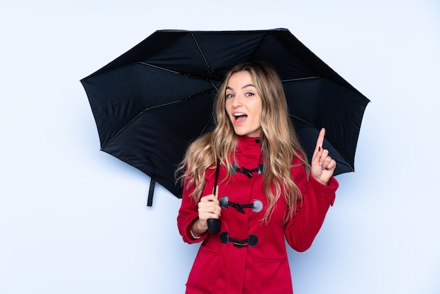 Jovem mulher segurando um guarda-chuva sobre parede isolada