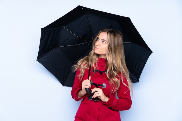 Jovem mulher segurando um guarda-chuva sobre parede isolada