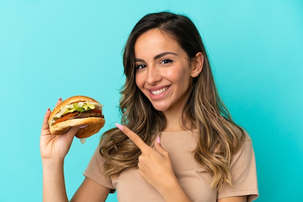 Jovem mulher segurando um hambúrguer sobre um fundo isolado