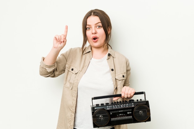 Jovem mulher segurando um rádio retrô, tendo uma ideia, conceito de inspiração.