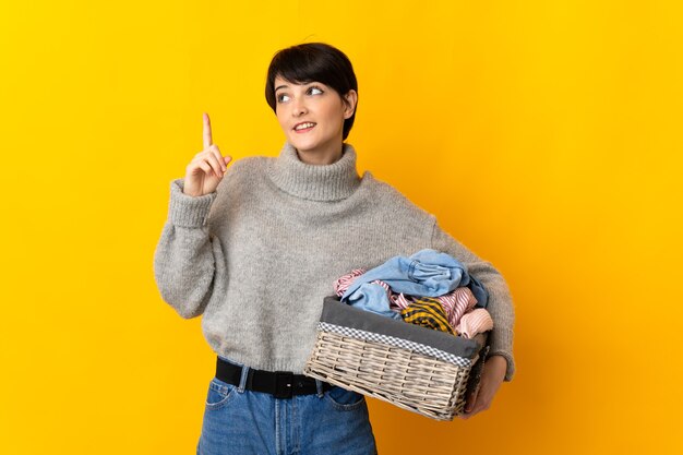 Jovem mulher segurando uma cesta de roupas apontando uma ótima ideia