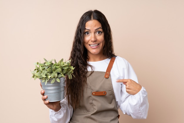 Jovem mulher segurando uma planta com expressão facial de surpresa