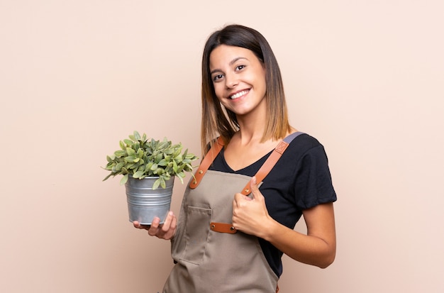 Jovem mulher segurando uma planta com polegares para cima porque algo bom aconteceu