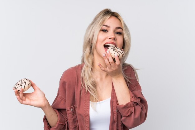 Jovem mulher segurando uma rosquinha sobre parede isolada