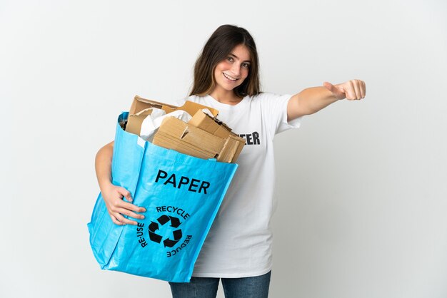 Jovem mulher segurando uma sacola cheia de papel para reciclar isolado no branco fazendo um gesto de polegar para cima