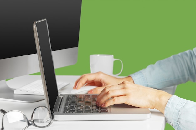 Jovem mulher sentada à mesa com o computador netbook aberto. Pessoa do sexo feminino usando tecnologia moderna.