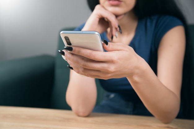 Jovem mulher sentada à mesa com o telefone