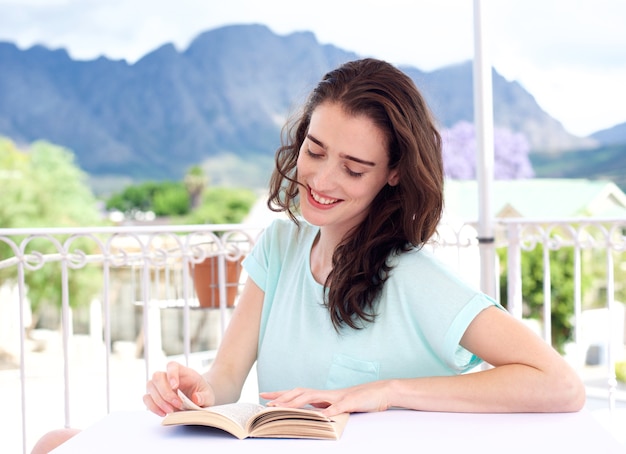 Jovem mulher sentada do lado de fora com café e livro