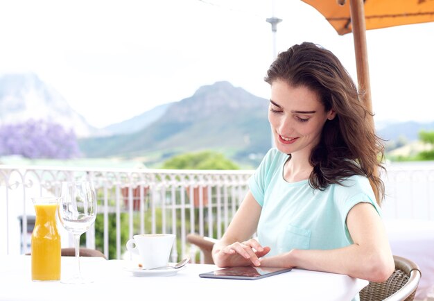 Jovem mulher sentada do lado de fora com café e livro