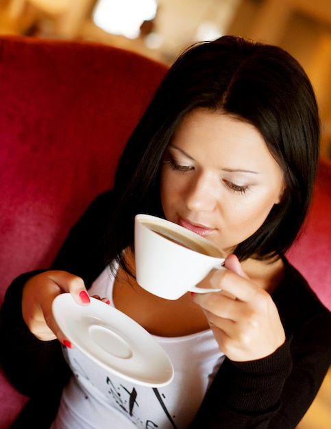 Jovem mulher sentada em um café bebendo café