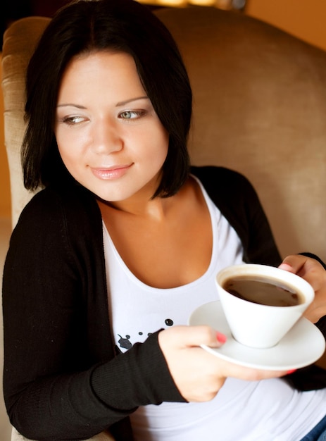 Jovem mulher sentada em um café bebendo café