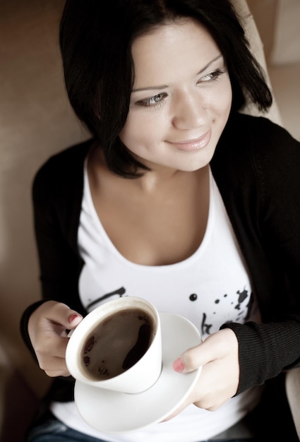 Jovem mulher sentada em um café bebendo café