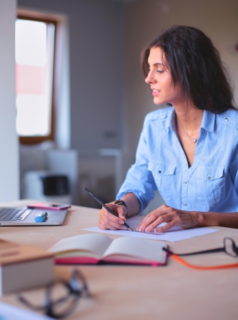 Jovem mulher sentada na mesa de escritório com laptop jovem mulher laptop