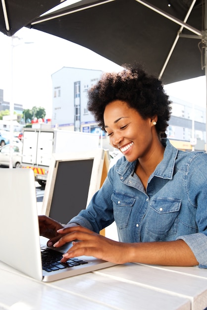 Jovem mulher sentada no café ao ar livre com laptop