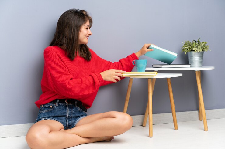 Foto jovem mulher sentada no chão e segurando um caderno