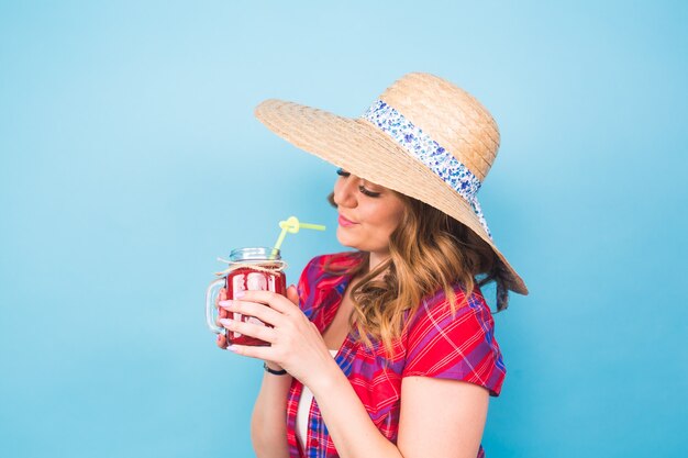 Jovem mulher sexy bebendo um batido saboroso sobre fundo azul e espaço de cópia, roupa vintage, retrato de estilo de vida de estúdio, sobremesa