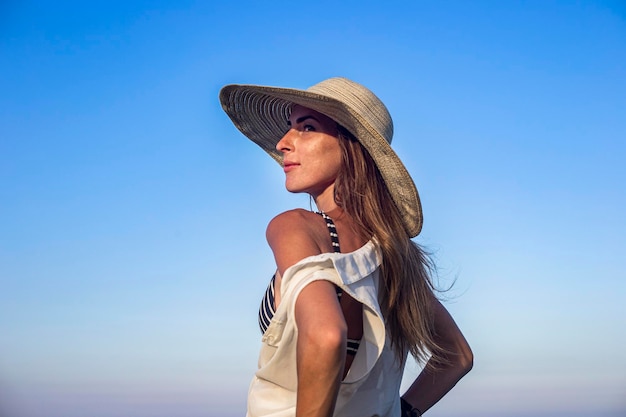 Jovem mulher sexy com chapéu no fundo do céu azul.