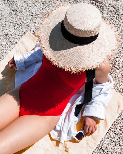 Jovem mulher sexy em maiô vermelho tomando banho de sol na praia do mar