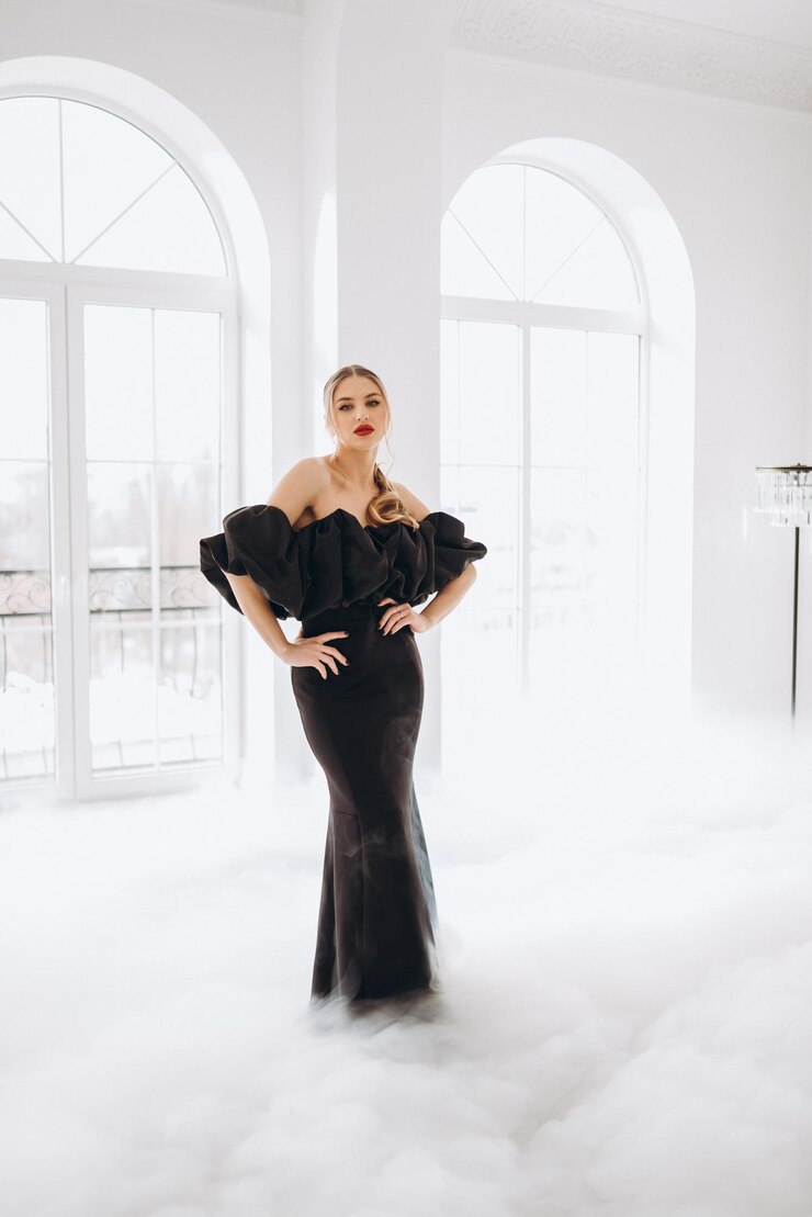 Foto jovem mulher sexy em um vestido longo preto elegante em uma sala iluminada perto da janela