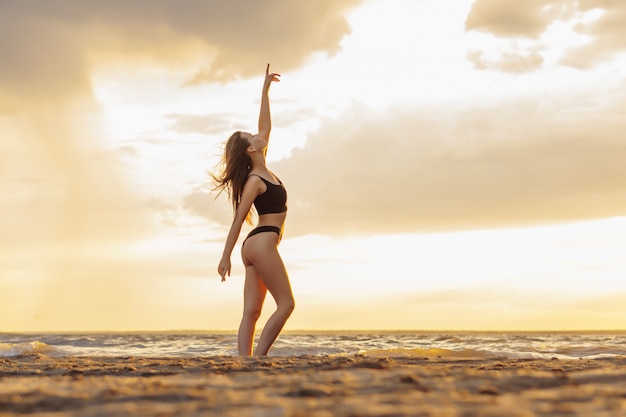 Jovem mulher sexy relaxante na praia por do sol.