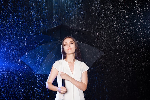 Foto jovem mulher sob o guarda-chuva. proteção contra chuva.