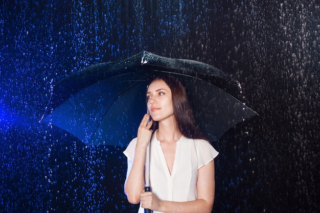 Jovem mulher sob o guarda-chuva. Proteção contra chuva.