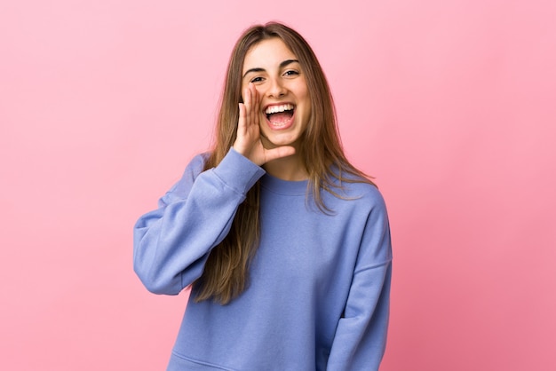 Jovem mulher sobre fundo rosa isolado, gritando com a boca aberta