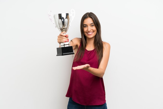 Foto jovem mulher sobre parede branca isolada, segurando um troféu